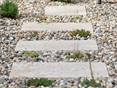 Gartenweg aus Travertinplatten in einem Kiesbett