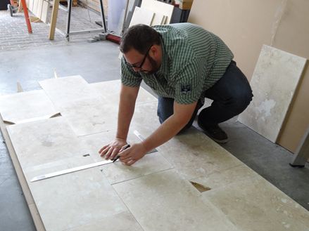 Adalbert Lange markiert die Fehlstellen der Fliesen, um sie danach als Bahnenware zurechtzuschneiden