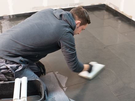 Fliesenleger reinigt den Boden