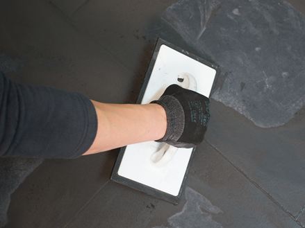 Fugen von dunklen Fliesen werden verspachtelt