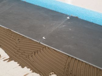 Fugenkreuze als Abstandshalter zwischen zwei Schieferfliesen