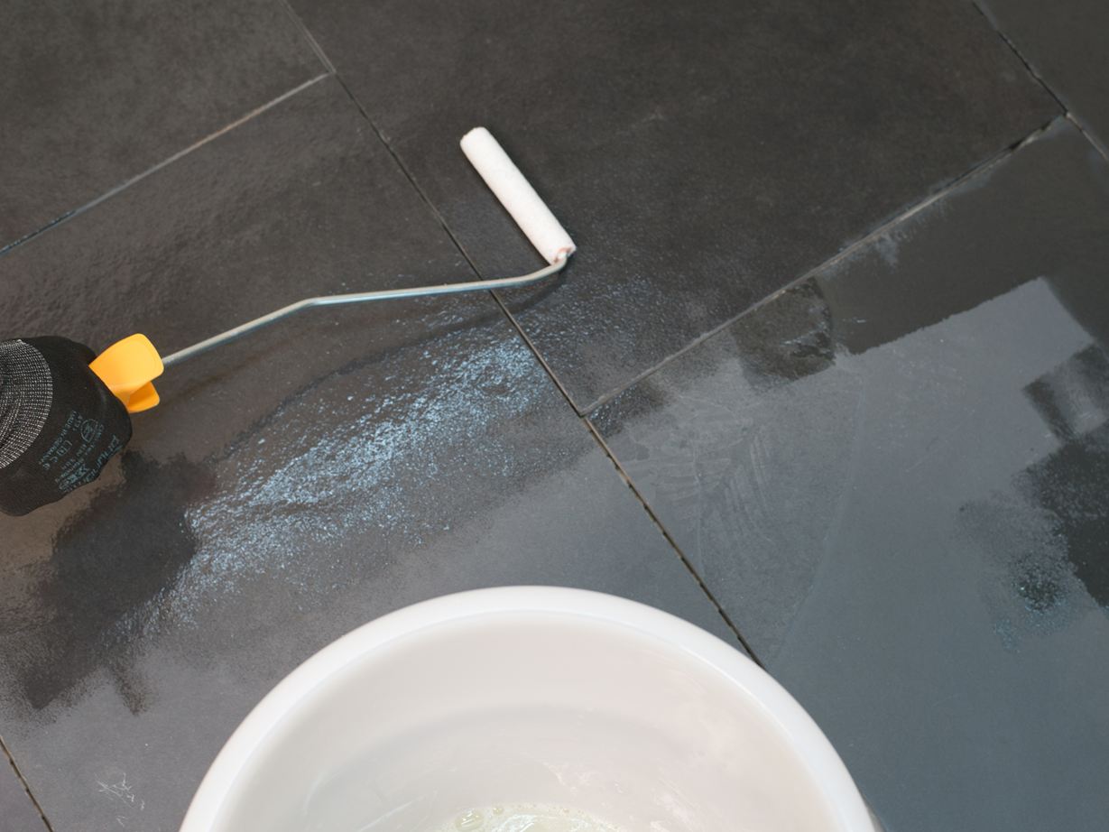 Imprägniermittel wird mit einer Rolle auf den verlegten Stein aufgetragen