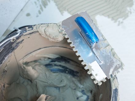 Ein Eimer mit Natursteinkleber und Zahntraufel