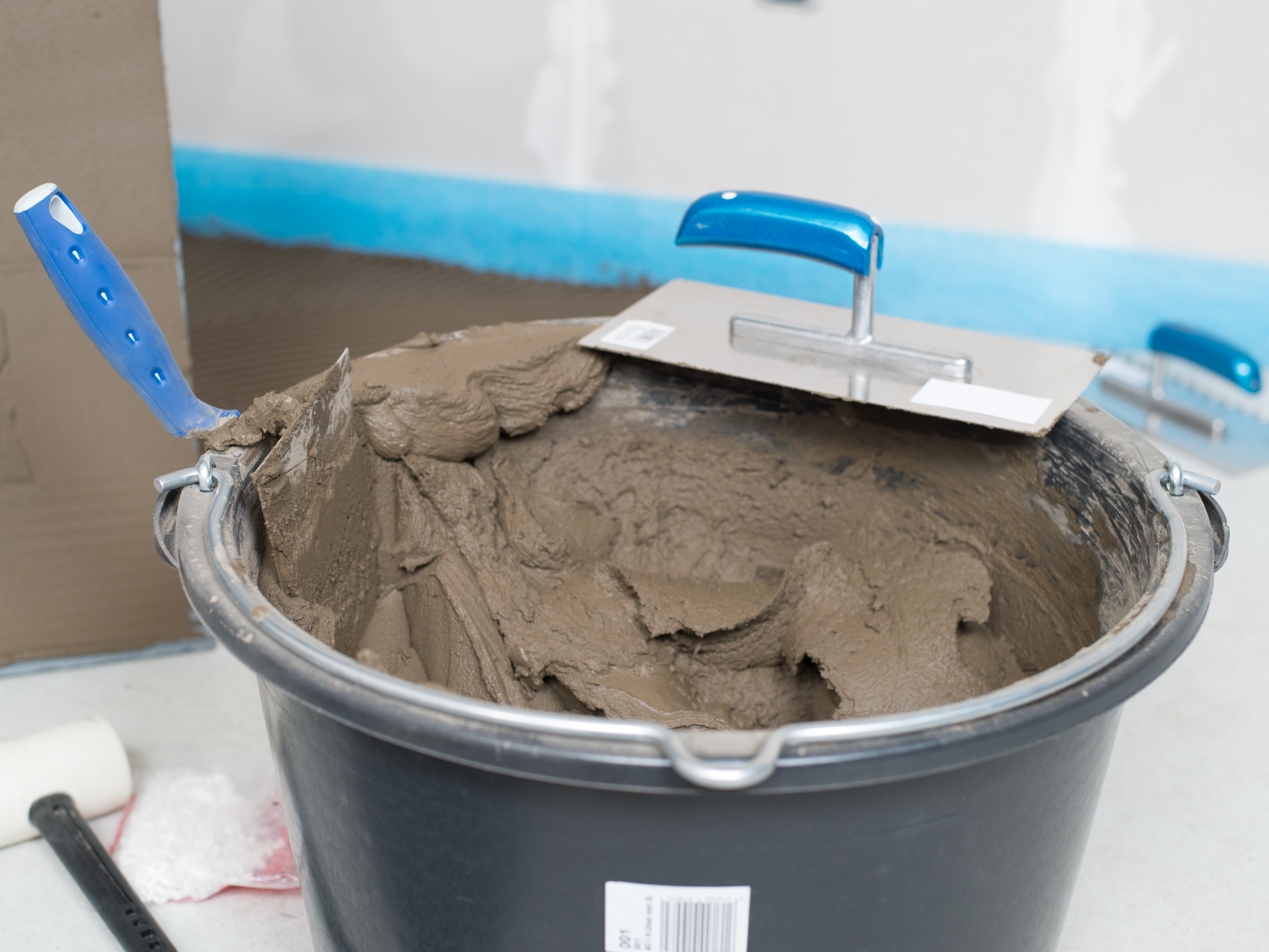 Ein Eimer mit Natursteinkleber und Zahntraufel