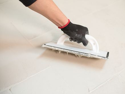 Eine Hand verfugt einen Travertinboden