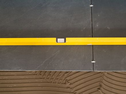 Eine Wasserwaage liegt bei der Verlegung auf Schieferfliesen