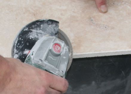 Mit einem Winkelschneider wird eine Steinplatte gesägt