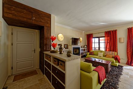 Wohnzimmer in mediterranem Wohnstil mit grüner Couch und roten Vorhängen