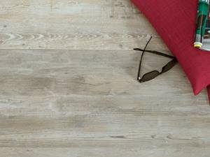 Ein natürlicher Terrassenboden zum Relaxen Helle Platten aus Feinsteinzeug in Holzoptik mit Brille und rotem Kissen