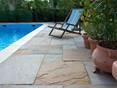 Die verschiedenen Farbtöne des Sandsteins ergeben ein harmonisches Gesamtbild Liegestuhl und mediterrane Pflanzen auf Natursteinplatten aus hellem Sandstein direkt am Pool