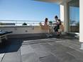 Die Schieferplatte Black Rustic harmoniert auch mit modernen Elementen! Frau und Kind sitzen an einem Tisch auf der Dachterrasse mit Naturschiefer