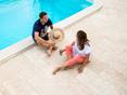 Die Terrassenplatten aus Naturstein wirken harmonisch und modern! Mann und Frau sitzen am Pool, Bodenbelag Travertin Terrassenplatten