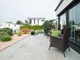 Terrassenplatten aus Travertin laden zum Relaxen im Garten ein. Terrasse mit modernem Steingarten und holzähnlichen Travertinplatten als Bodenbelag