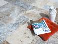 Die Vielfalt der Farben des Travertins Silver schafft dieses harmonische und rustikale Ambiente. Rotes Kissen mit Zeitschrift und eine weiße Vase auf silbergrauen Natursteinplatten Travertin