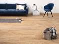 Urban Honey ist für beide rustikale und moderne Einrichtungsstile geeignet. Wohnzimmer mit Feinsteinzeugfliesen Urban Honey und blauer Couch mit passendem Stuhl, im Vordergrund eine Tasche