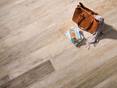 Die Verlegung dieser Holzoptikfliese ist besonders einfach. Tasche auf verlegten Fliesen aus Feinsteinzeug in braun-beiger Holzoptik