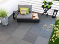 Terrasse mit moderner Couch und Platten aus Feinsteinzeug in Schieferoptik von oben
